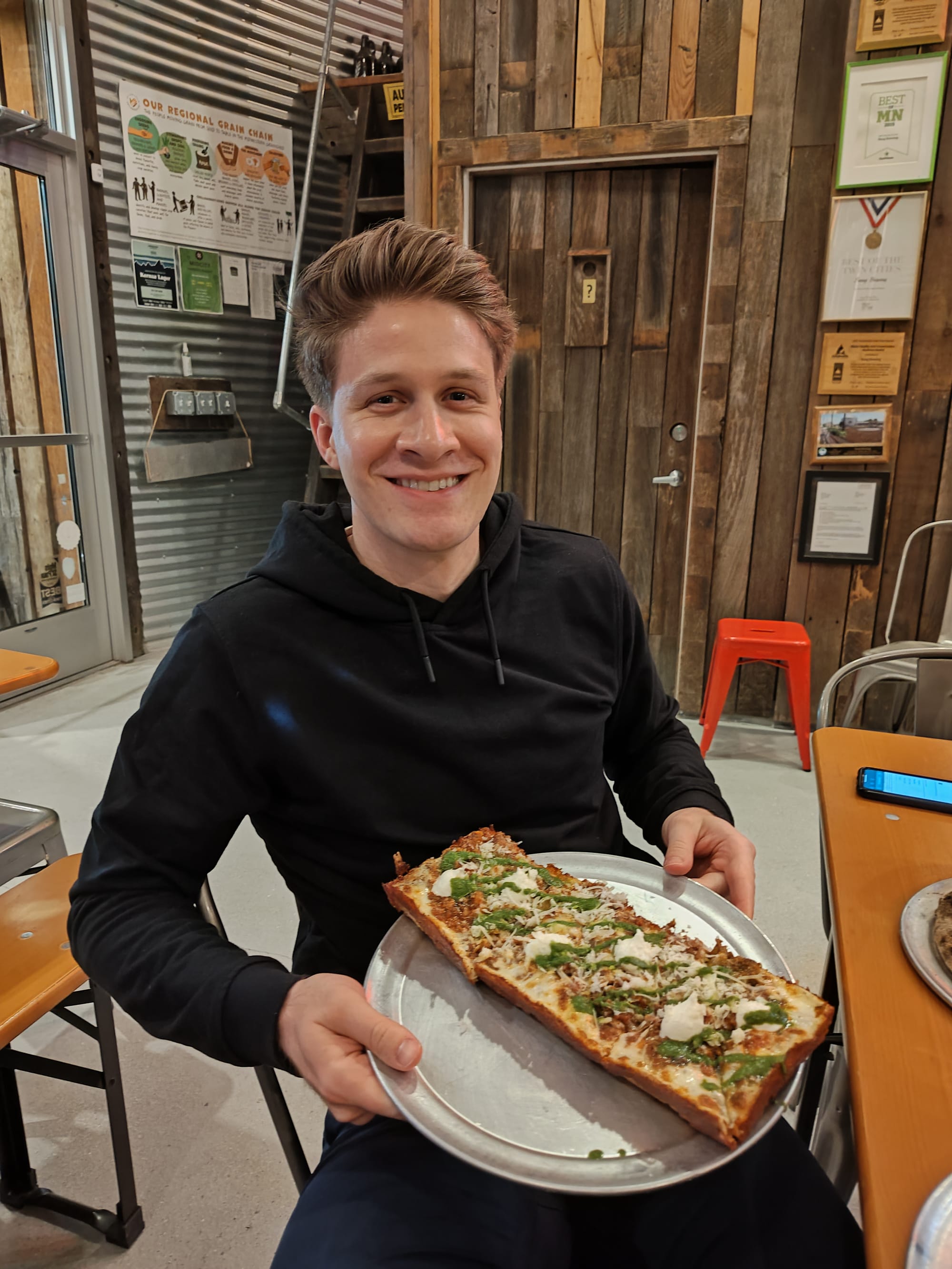 man holding a detroit-style pizza