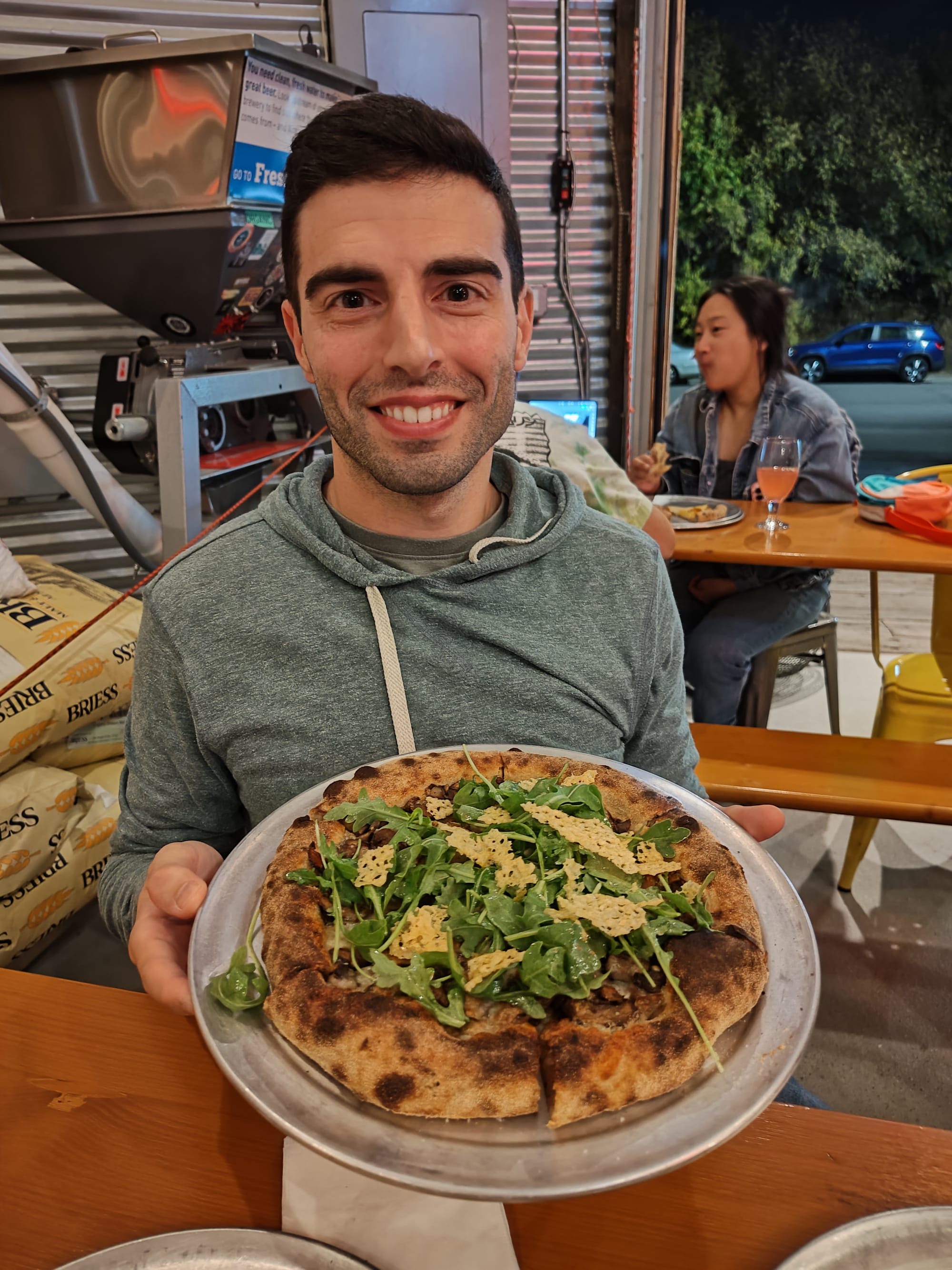 man holding a complete, mushroom pizza