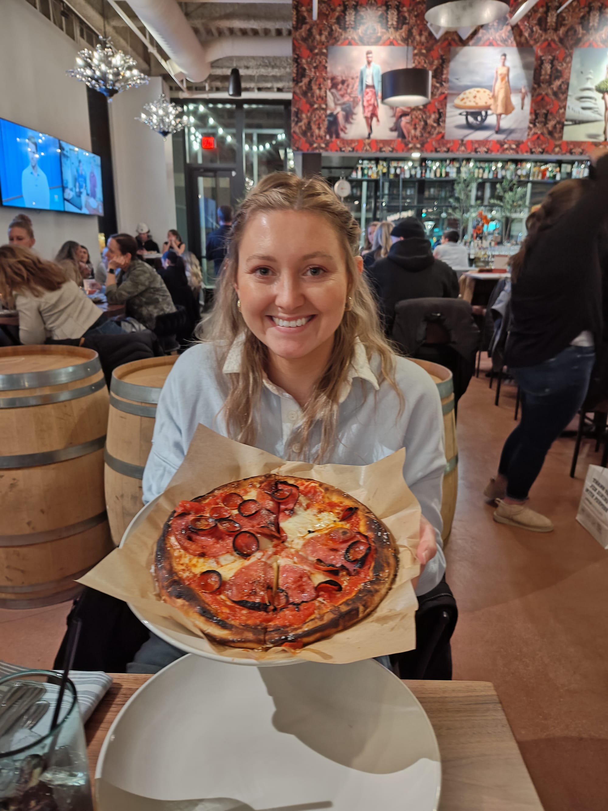 woman holding a meat pizza